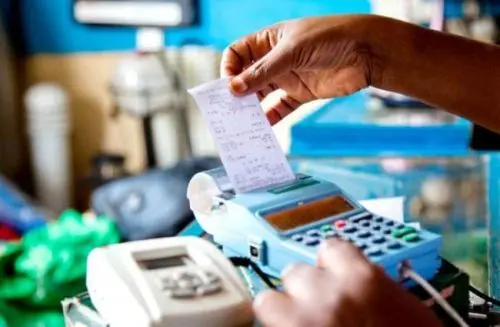wpid-trader.jpg A trader retrievesa receipt from an EBM. The amended law reinforces ministerial powers to fine taxpayers who circumvent using electronic billing machines to avoid paying taxes. (File)